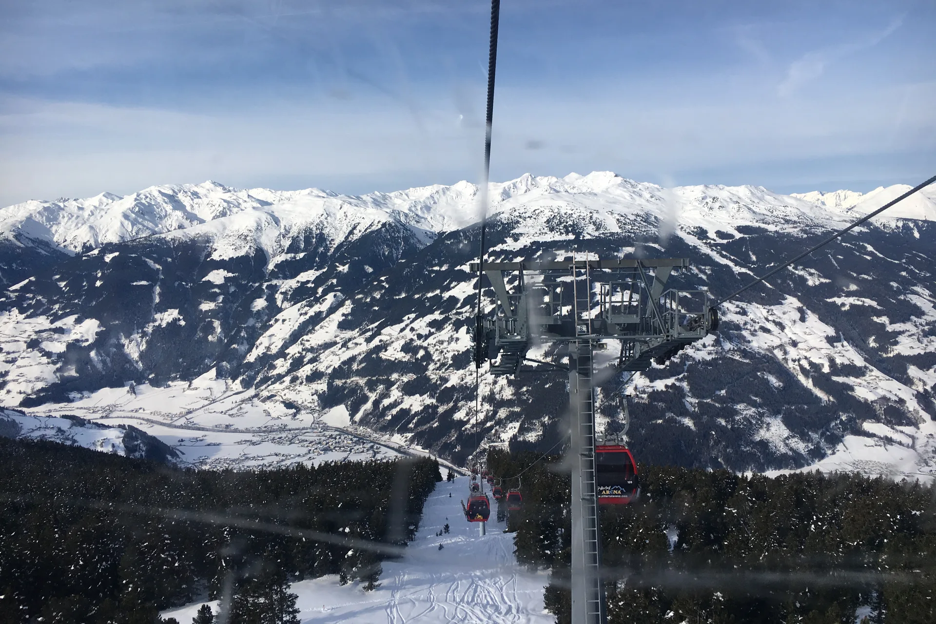 Rode gondels van de Karspitzbahn boven de besneeuwde hellingen en het dal bij Zell am Ziller.